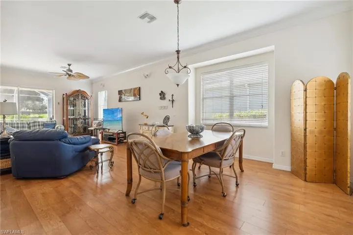 Dining room with light wood-type flooring, ceiling fan, and ornamental molding