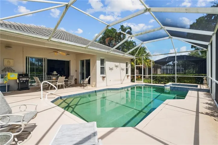 View of swimming pool featuring glass enclosure, ceiling fan, and a patio area