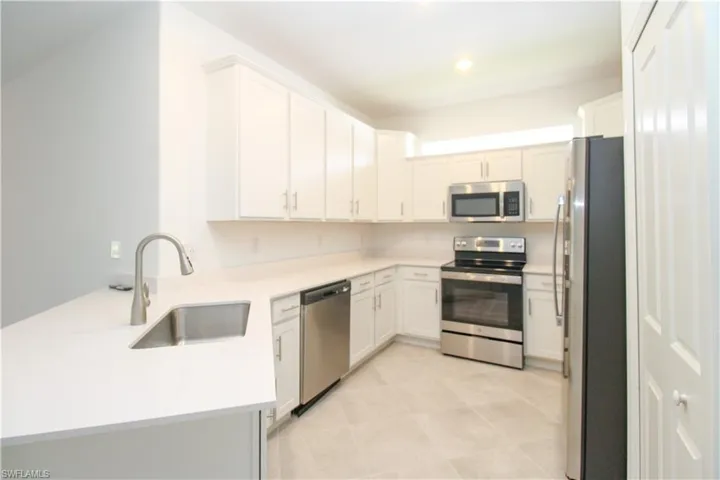 Kitchen featuring white cabinets, sink, appliances with stainless steel finishes, and light tile patterned floors