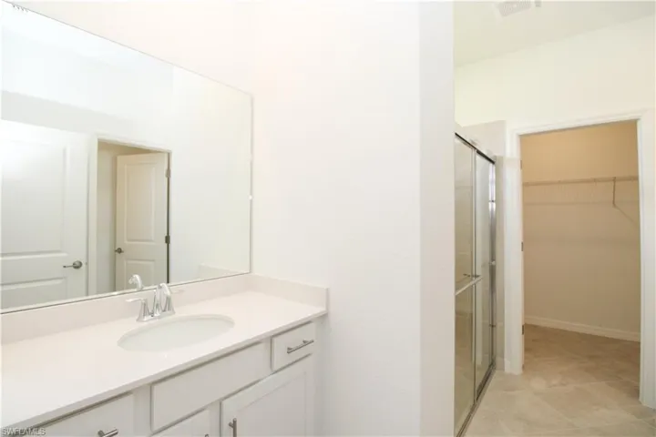 Bathroom with vanity, tile patterned floors, and a shower with door