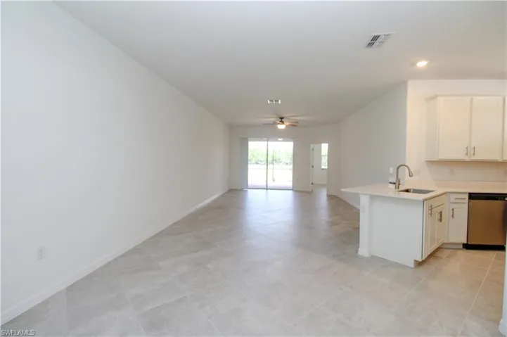 Kitchen featuring white cabinetry, light tile patterned floors, dishwasher, ceiling fan, and sink