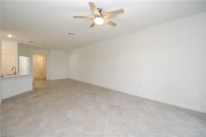 Empty room with sink, light tile patterned floors, and ceiling fan