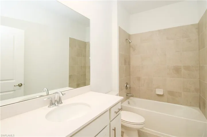 Full bathroom featuring vanity, tiled shower / bath, and toilet