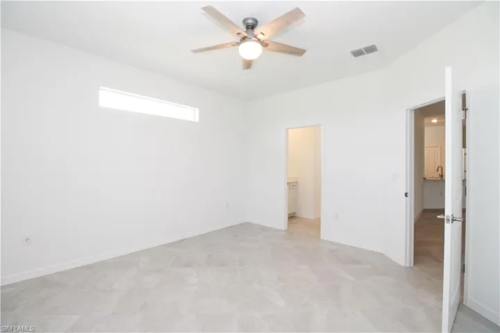 Unfurnished bedroom featuring a closet, a walk in closet, light tile patterned floors, and ceiling fan