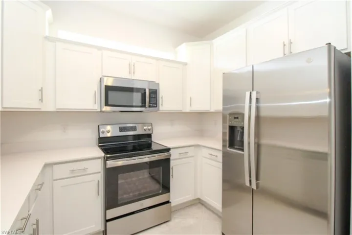 Kitchen featuring appliances with stainless steel finishes, light tile patterned floors, and white cabinets