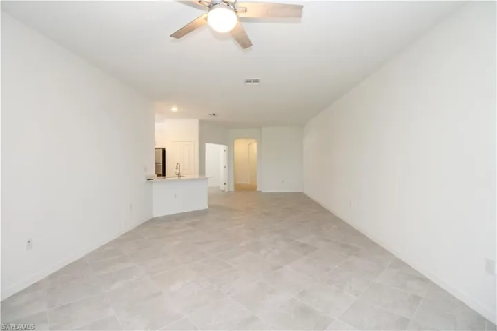 Unfurnished living room featuring sink, light tile patterned floors, and ceiling fan