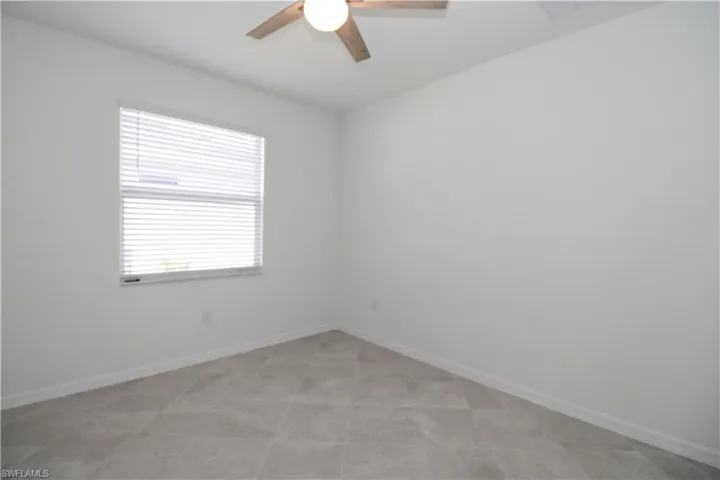 Empty room with light tile patterned floors and ceiling fan