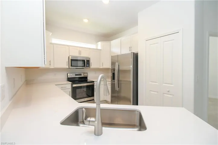 Kitchen with white cabinetry, stainless steel appliances, and sink