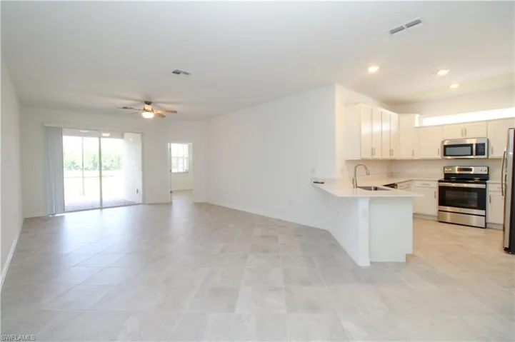 Kitchen with appliances with stainless steel finishes, kitchen peninsula, ceiling fan, and light tile patterned floors