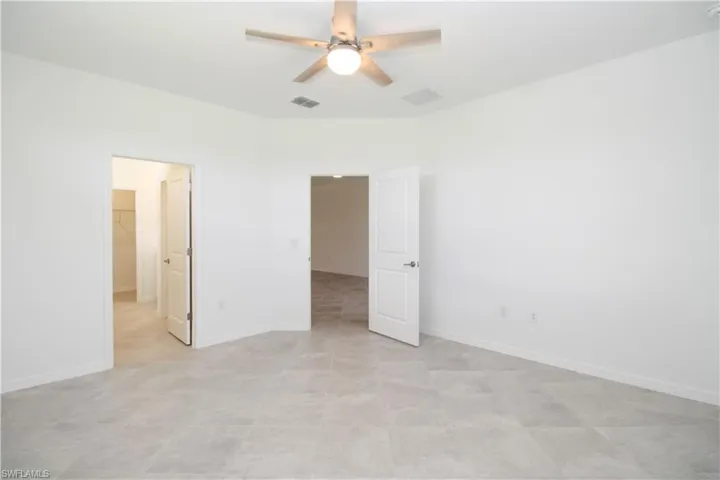 Unfurnished bedroom with light tile patterned floors, a spacious closet, and ceiling fan