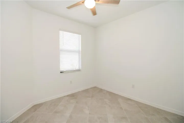 Tiled empty room featuring ceiling fan
