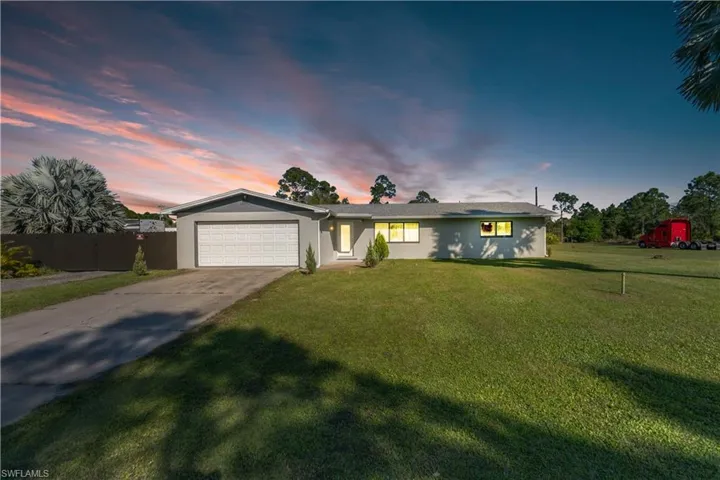 Ranch-style house with stucco siding, concrete driveway, a lawn, fence, and a garage