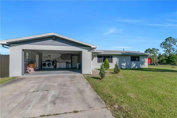 Ranch-style home with a garage, a front yard, driveway, and stucco siding