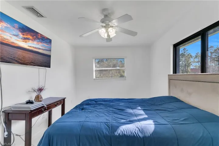 Bedroom with visible vents, ceiling fan, and multiple windows