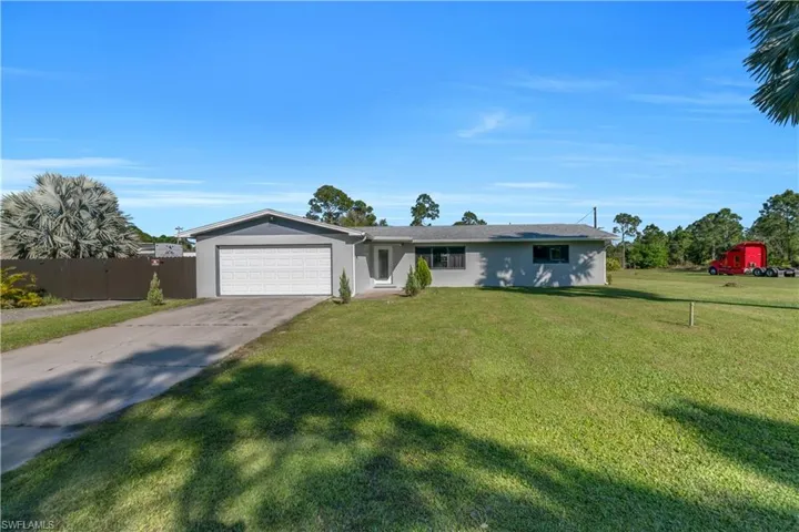 Single story home with a front yard, concrete driveway, an attached garage, and stucco siding