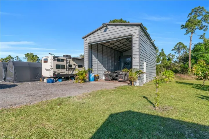 View of outbuilding featuring driveway, a carport, and an outbuilding