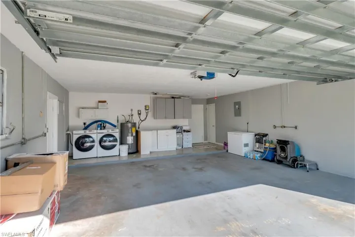 Garage featuring water heater, washer and clothes dryer, electric panel, and a garage door opener