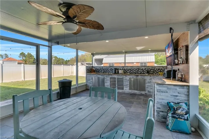 View of patio featuring ceiling fan, a fenced backyard, outdoor dining area, and exterior kitchen