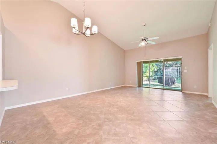 Spare room featuring lofted ceiling, a ceiling fan, a chandelier, and light tile patterned floors