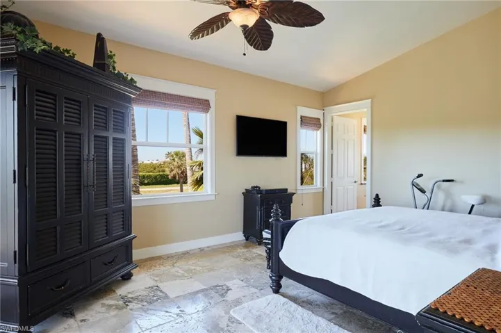 Primary bedroom with windows and sliders to screened balcony
