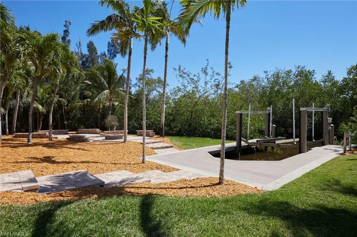 View of the backyard with paver patio, seating, firepit and boat dock with lift.