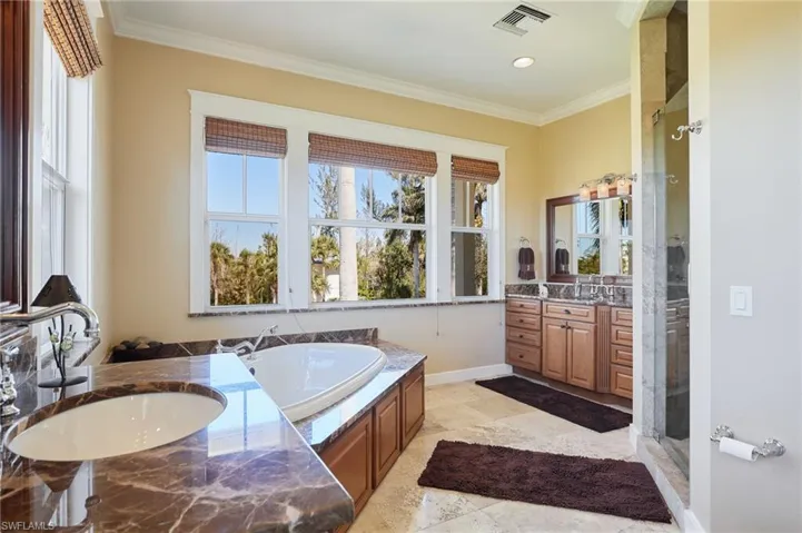 Bathroom with a healthy amount of sunlight, his and her sinks, separate shower and jetted tub
