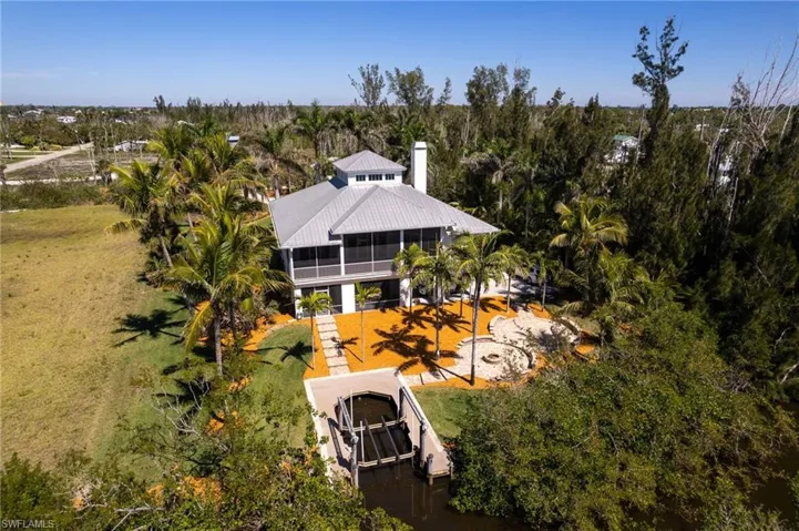 Rear view of the property showing screened balcony, paver patio with firepit and boat dock with lift.