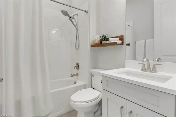 Full bathroom with vanity, shower / bath combination with curtain, and toilet
