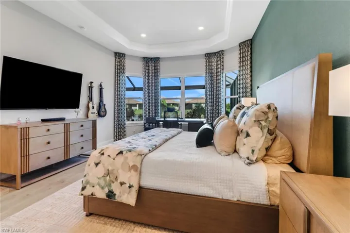Bedroom with a raised ceiling and light wood-type flooring