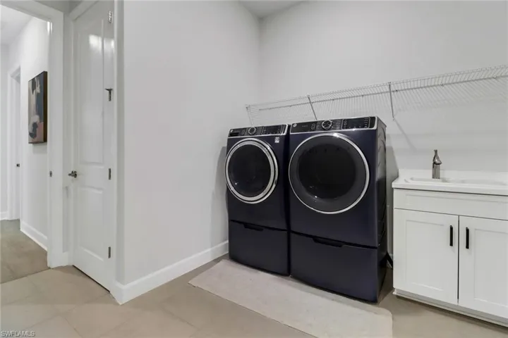 Laundry room with light tile patterned floors, sink, and washing machine and clothes dryer