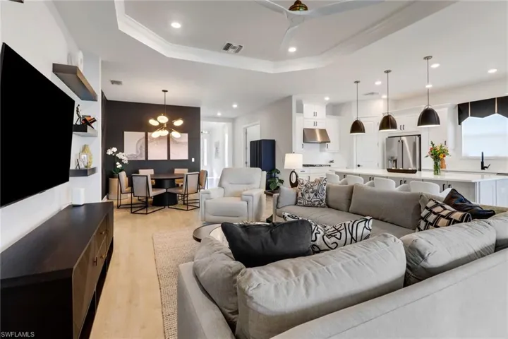 Living room with a tray ceiling, an inviting chandelier, and light wood-type flooring