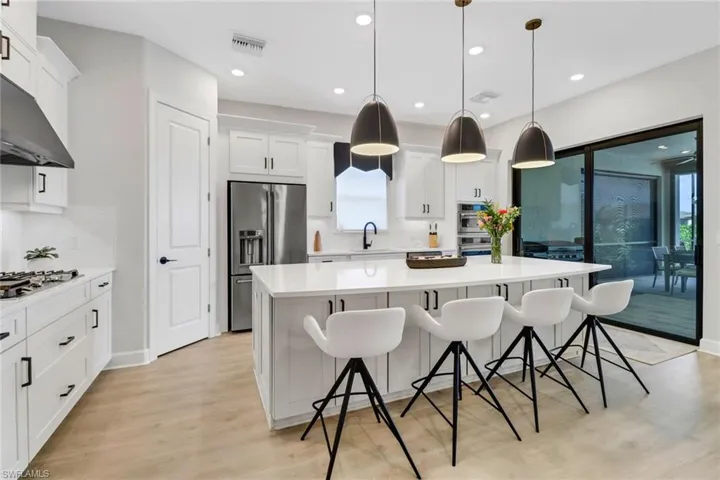 Kitchen with hanging light fixtures, backsplash, stainless steel appliances, and a wealth of natural light