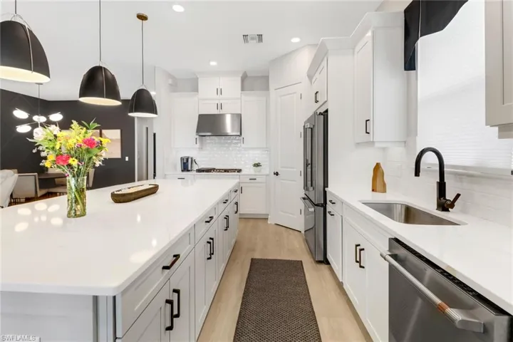 Kitchen with a center island, sink, light hardwood / wood-style flooring, white cabinetry, and stainless steel appliances