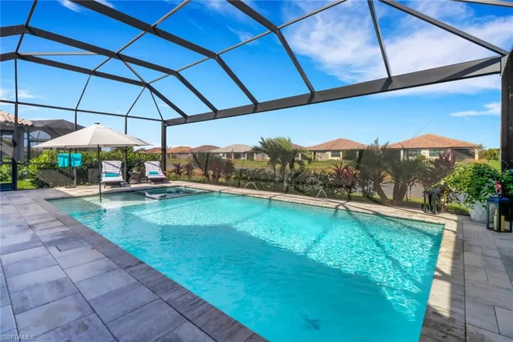 View of swimming pool with glass enclosure, a patio area, and an in ground hot tub