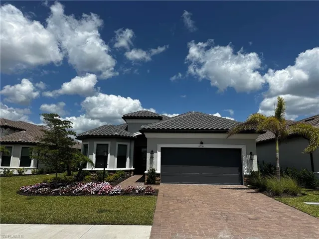 View of front of property with stucco siding, an attached garage, a tile roof, decorative driveway, and a front yard