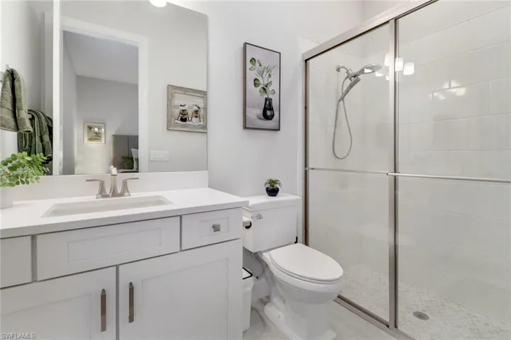 Bathroom featuring vanity, a shower with shower door, and toilet