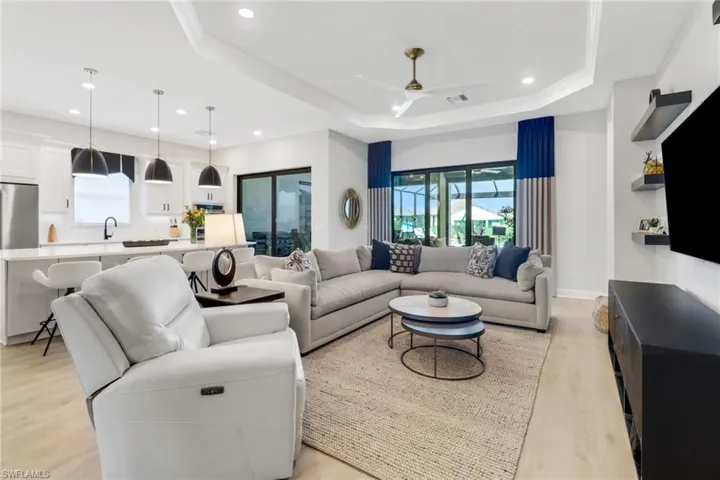 Living room with ceiling fan, light hardwood / wood-style floors, and a tray ceiling