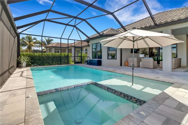 View of pool featuring a lanai, a patio area, an in ground hot tub, and an outdoor living space