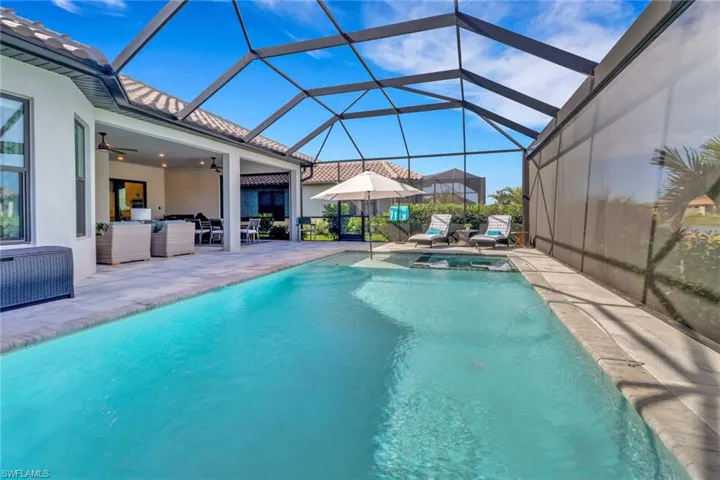 View of swimming pool featuring an in ground hot tub, glass enclosure, ceiling fan, and a patio area