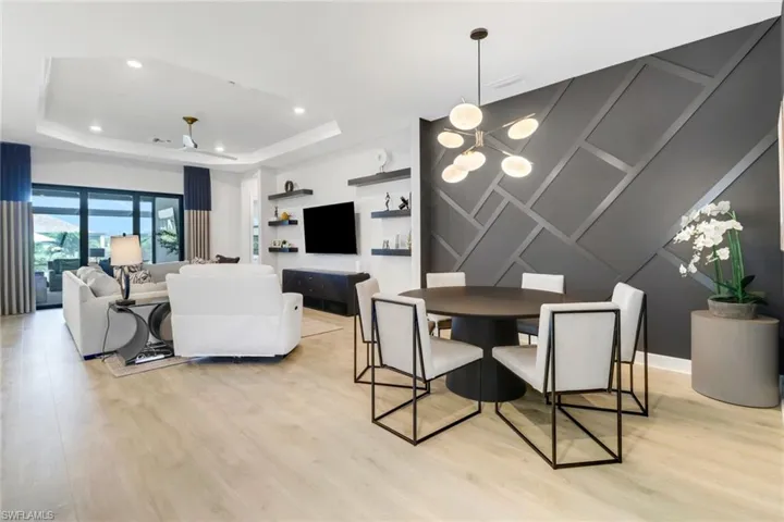 Dining area with light wood-type flooring and a tray ceiling