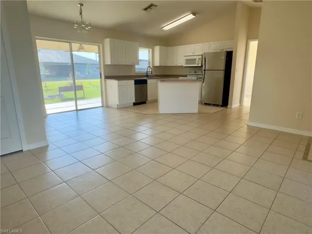 Kitchen featuring light tile flooring, lofted ceiling, and appliances with stainless steel finishes