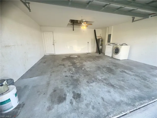 Garage with water heater, washing machine and dryer, a garage door opener, and ceiling fan