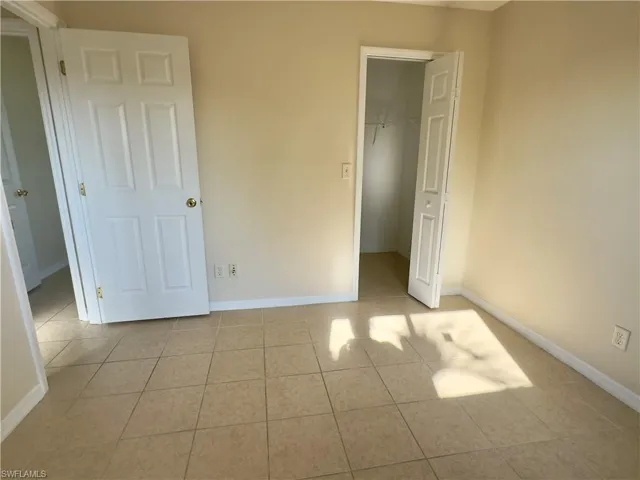 Unfurnished bedroom with a closet, a walk in closet, and light tile floors