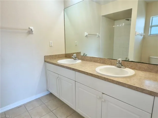 Bathroom with tile floors, toilet, and dual bowl vanity