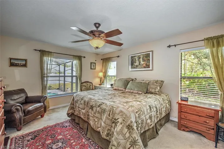 Bedroom with light colored carpet, a textured ceiling, and ceiling fan