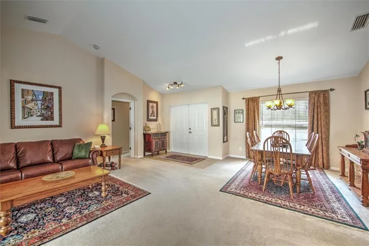 Carpeted dining room featuring lofted ceiling and a chandelier