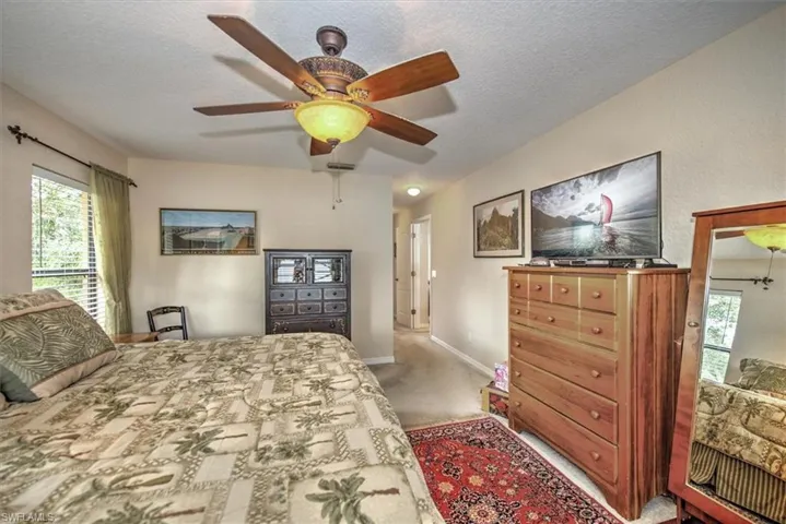 Carpeted bedroom featuring ceiling fan and a textured ceiling