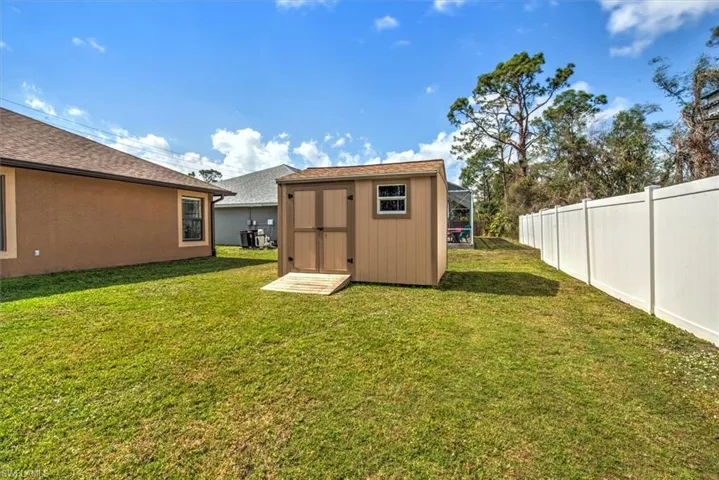 View of yard featuring central AC and a storage unit