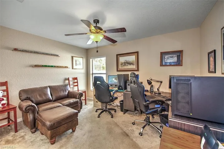 Carpeted office space with a textured ceiling and ceiling fan