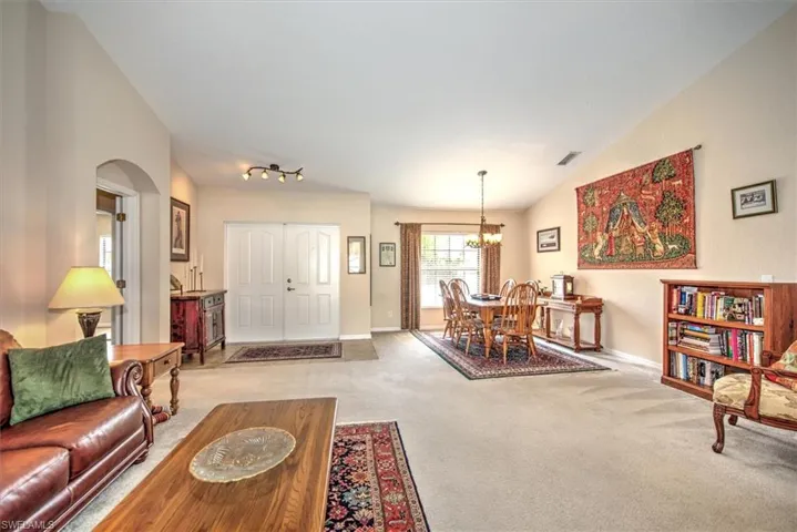 Carpeted living room featuring lofted ceiling and a chandelier
